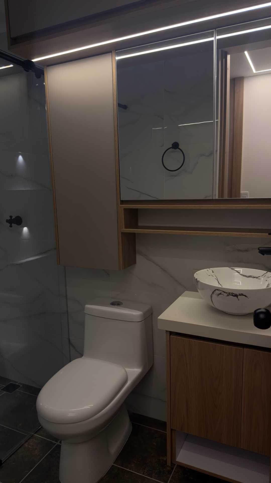 Baño en mármol con mobiliario en madera
