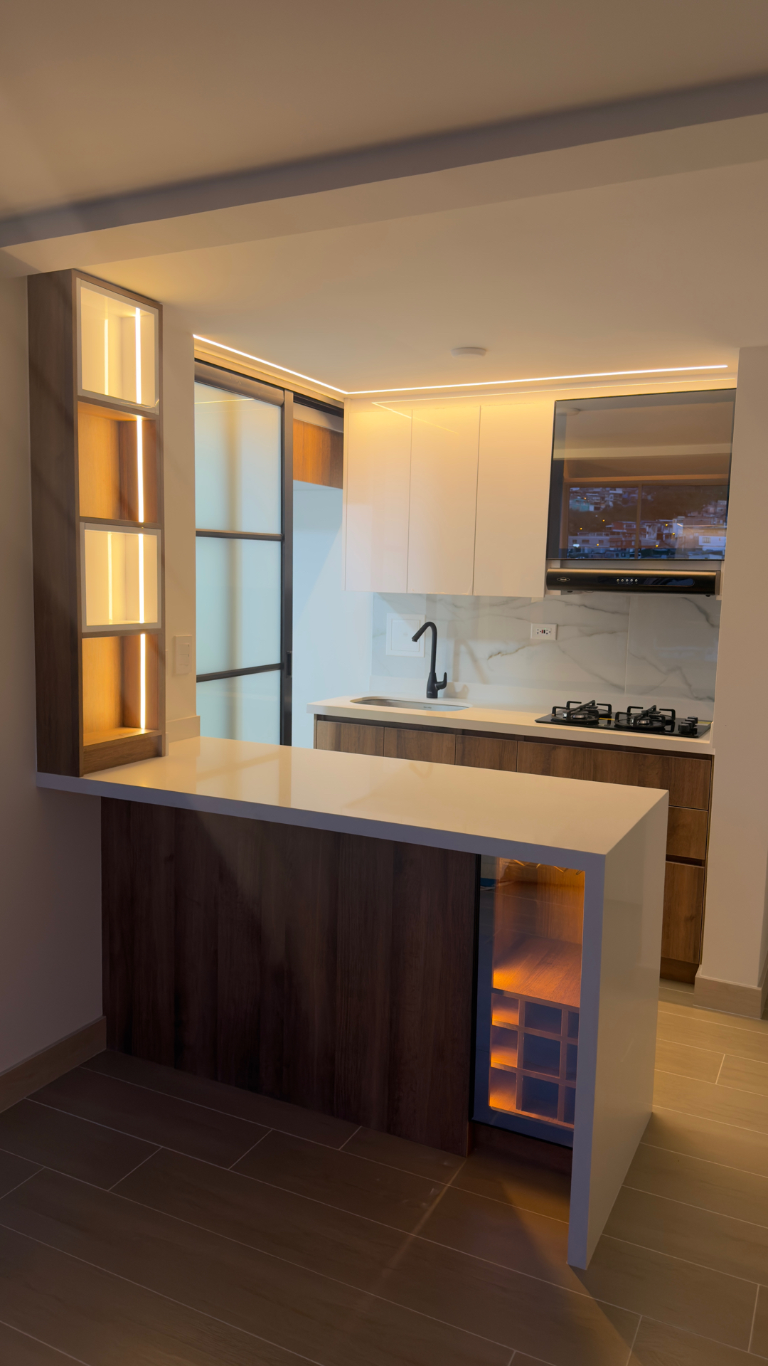 Cocina abierta con barra, vinoteca y columna de nichos LED