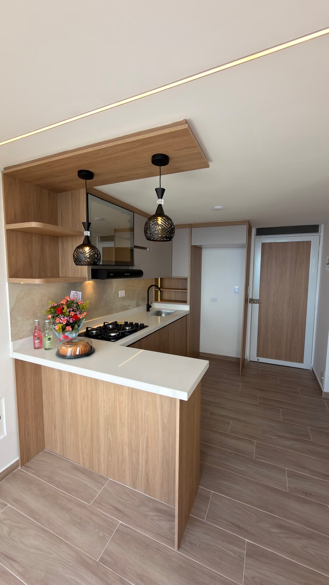 Cocina en U con plafón en madera, lámparas decorativas y módulos en gris